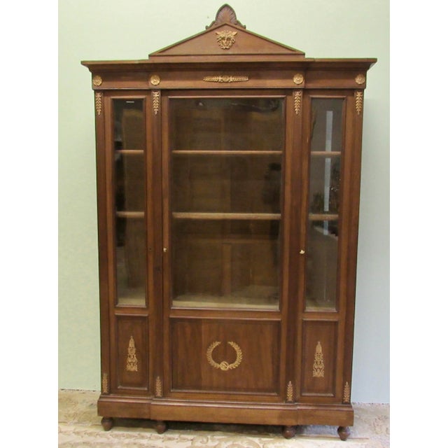 This is an Antique French Empire Red Mahogany Three Glass Door Bookcase With Three Adjustable Shelves. The bookcase...