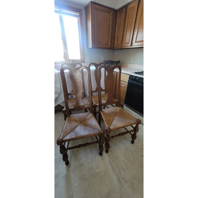 Vintage French Provincial style chairs featuring woven rush seats, carved back splats, and carved wood, likely maple or...