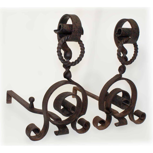 Large antique hand wrought iron andirons having scroll and ring motifs with chain.