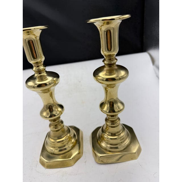 Pair of vintage solid brass candlesticks featuring a classic baluster design and octagonal bases. Each candlestick...