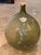 A blown green glass demijohn with a shield reading "Beaune 1781." Cork stopper with burlap collar.