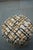 Cozy, modern pouf with a plush, textured fabric in a neutral cream base accented by black and warm brown tones. Supported...