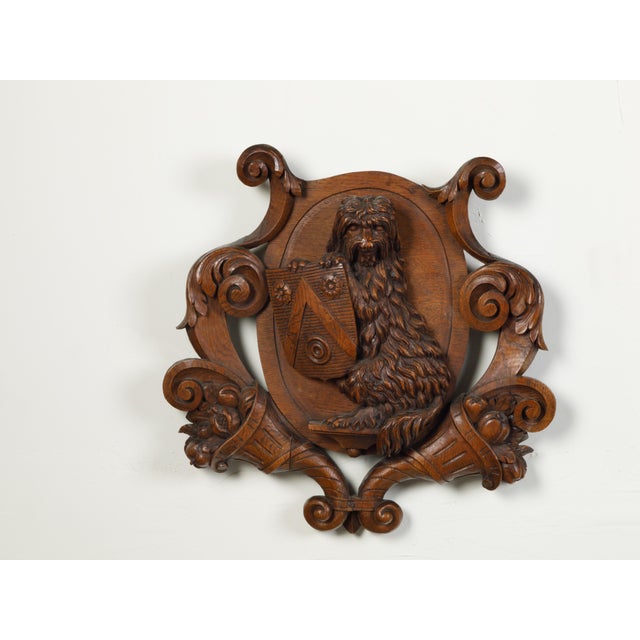 An English carved wooden wall fragment from the late 19th century, depicting a dog with a shield and cornucopia. Created...