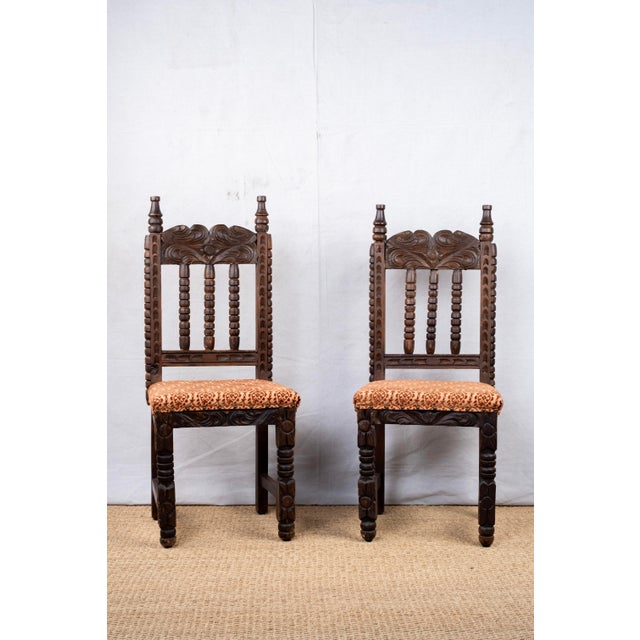 Pair of carved wood side chairs, late 19th century, Spanish. Seats are upholstered with spaced nailheads. The back of one...