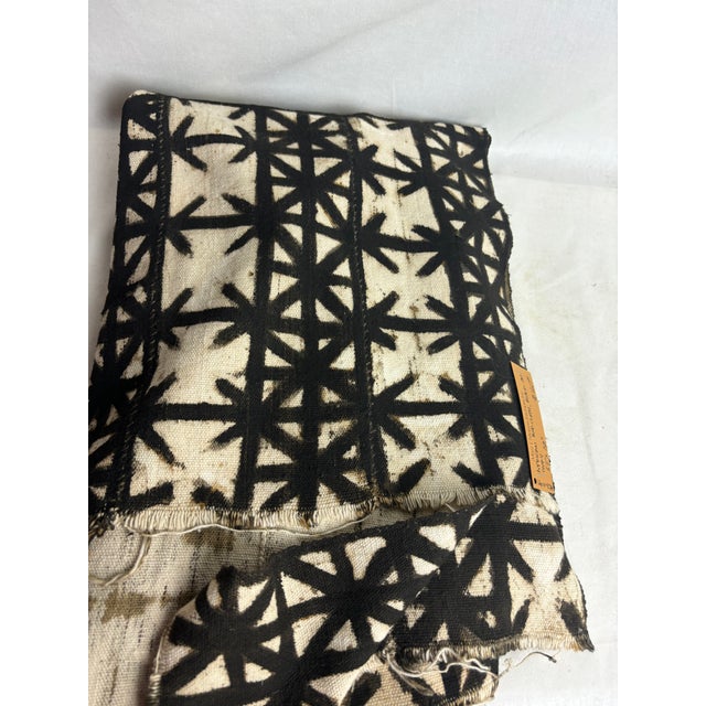This gorgeous African Mud Cloth features black decals on ivory woven fabric. The raw, short-tasseled edge creates a...