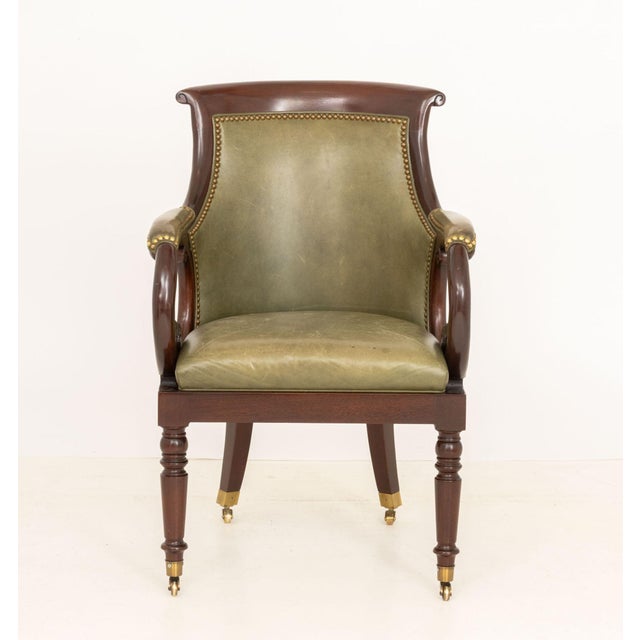 Hancock and Moore Jockey Club Chair, with studded brass nailhead trim, olive green leather upholstery, and atop casters,...