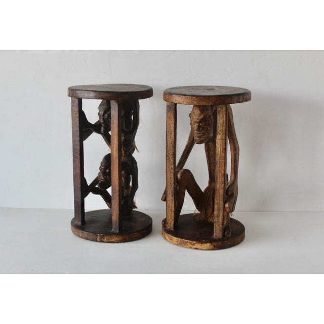 Vintage African hand-carved hardwood accent tables or plant stands featuring figural character carvings with round top and...