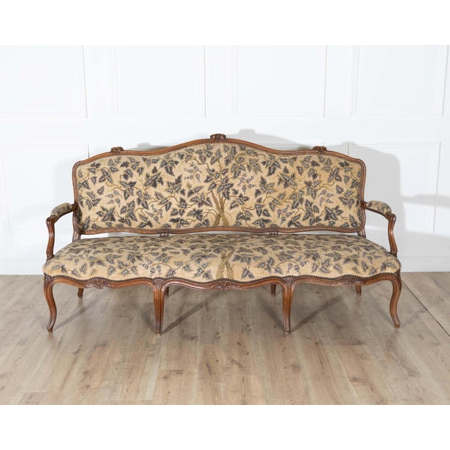 An elegant Louis XV period three-seat sofa from the Rhône Valley, beautifully crafted in solid walnut with graceful...