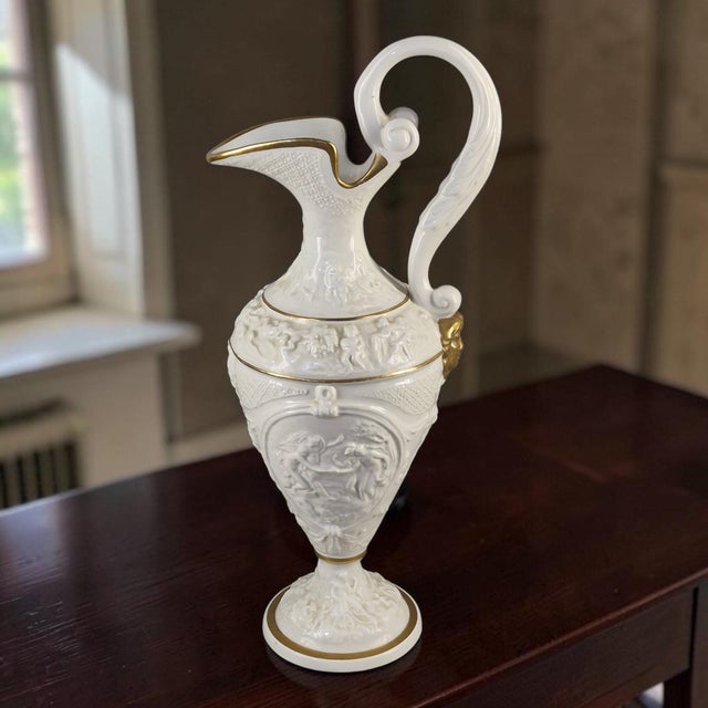 The Neo-Classical Ewer by Ardalt Capoimpero is a stunning piece of Italian bone china, adorned with a delicate figural...