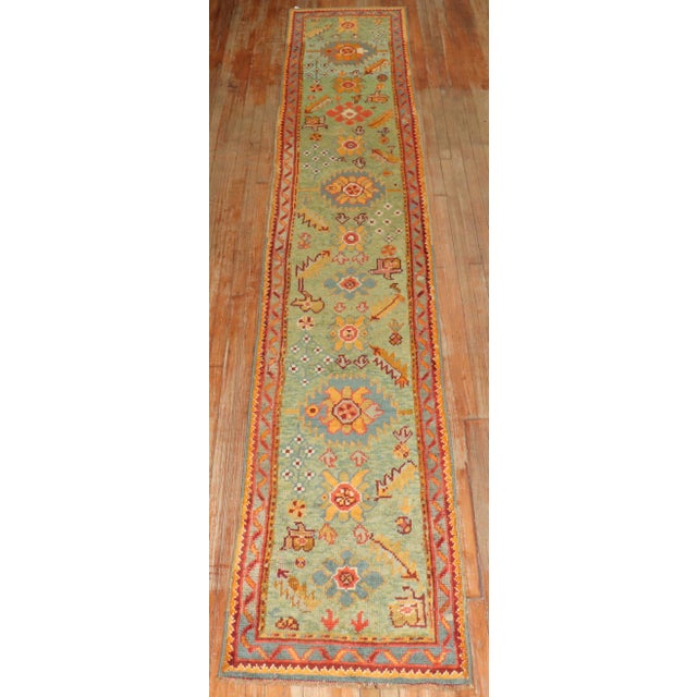 An early 20th century narrow and long bright green field Antique turkish oushak runner. Size 2'6'' x 15'1''.