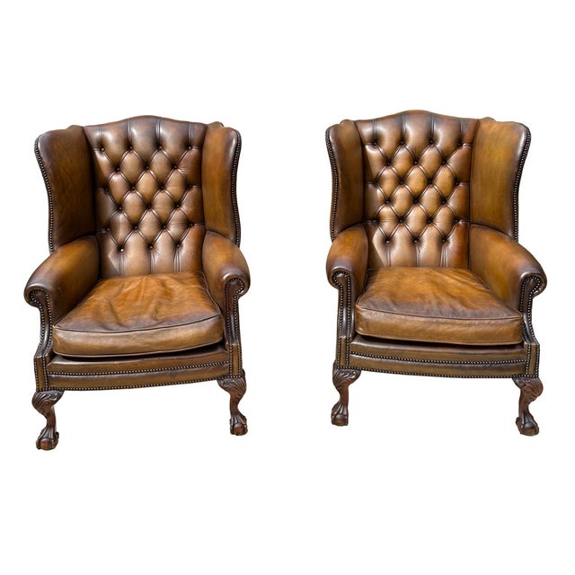 A pair of Edwardian Chippendale-style Leather Wingback Chairs, shaped and slanted, with hand-tied button tufting, trimmed...