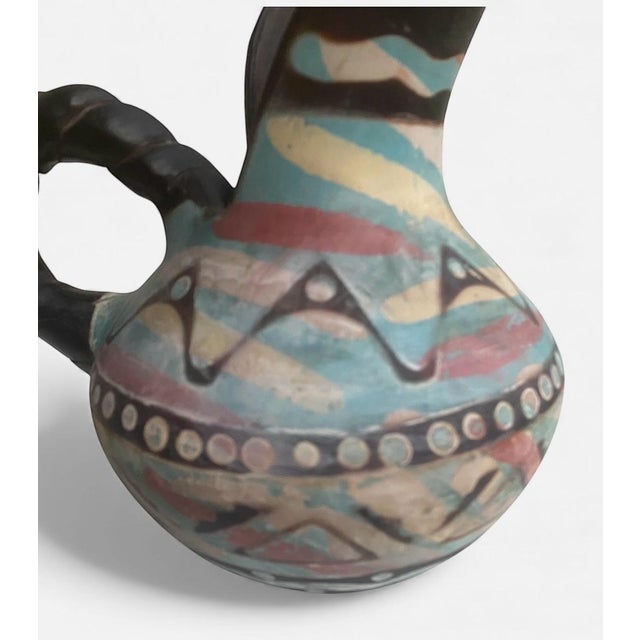 Beautiful handmade Peruvian pottery pitcher featuring bold geometric patterns in desert-inspired tones of turquoise, sand,...