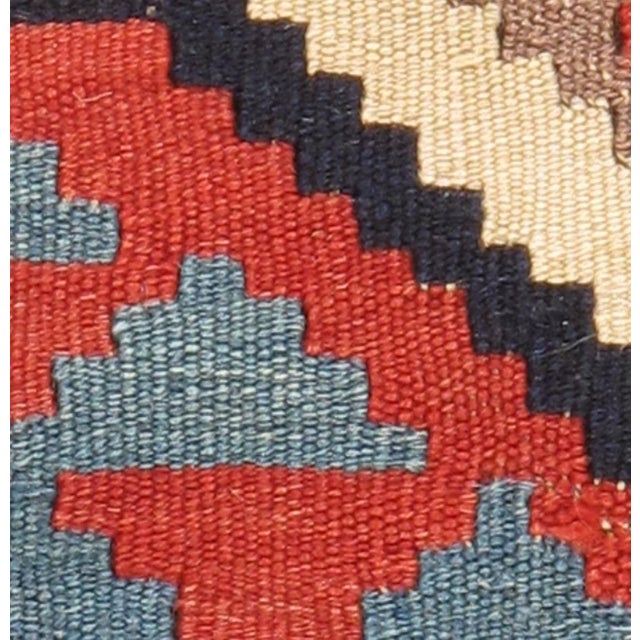Vintage handwoven Caucasian Shirvan kilim featuring a bold geometric pattern. The vibrant color palette includes shades of...