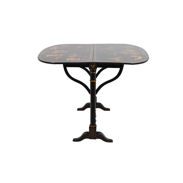 Chinese style leaf table in black lacquered wood with a gilt decor. Two leaves adorned with large cartouches framing...