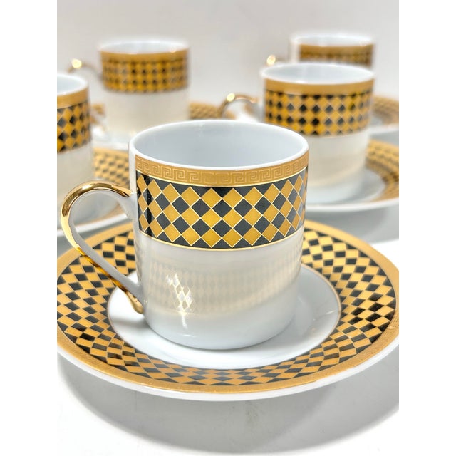 Vintage porcelain espresso set featuring six cups and matching saucers decorated in a bold black-and-gold harlequin...