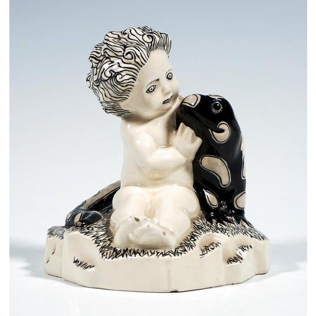 Excellent and rare art nouveau ceramic piece from the early 20th century: a nude putto seated on a rounded, irregularly...