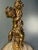 A romantic vintage table lamp featuring a sculptural antique gold-tone cherub / putti figural perched above an ivory-and-...
