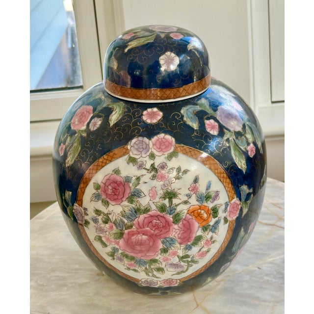 Vintage chinoiserie ginger jar with lid. Beautiful blue backdrop with a pretty floral design of pink, orange, and purple...