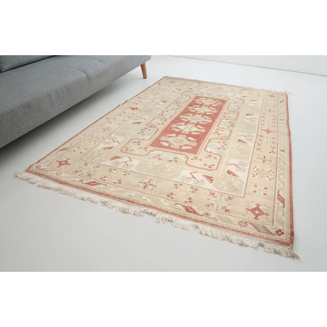 This is a vintage Turkish Oushak rug from the Mid 20th Century. The piece was hand-knotted.