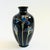 A petite glossy black vintage ceramic bud vase. Features a blue iris design outlined in metallic gold. Made in Japan by...