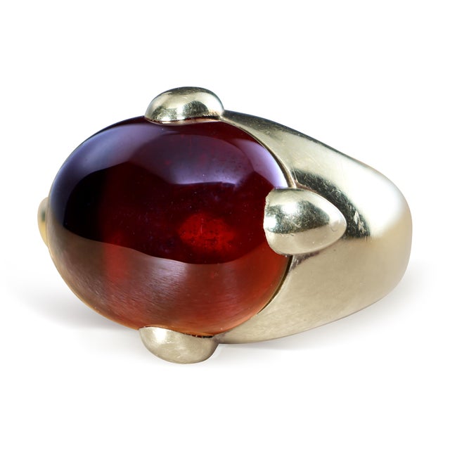 Circa 1970s Pomellato cocktail ring in 18K yellow gold, centered by a large oval cabochon hessonite garnet with a deep...