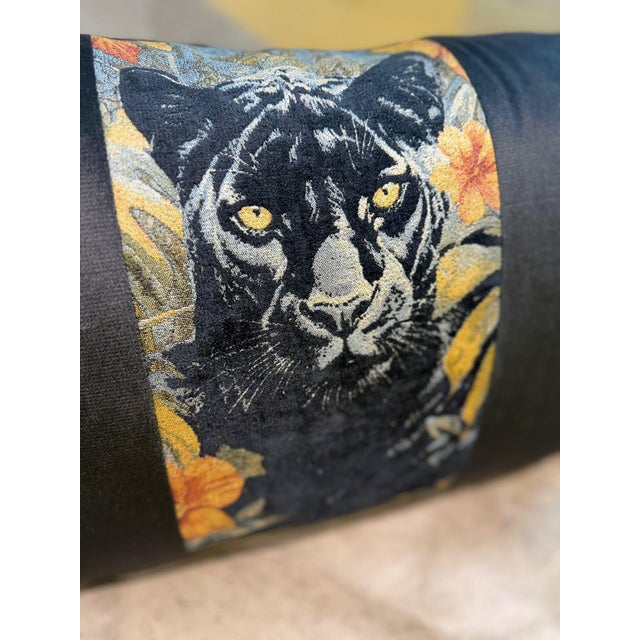 A lumbar cushion cover centered on a woven jacquard panel showing a black panther emerging from amber foliage and deep red...