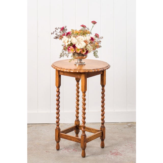 This antique English barley twist lamp table features a circular tabletop with a scalloped edge, supported by four turned...