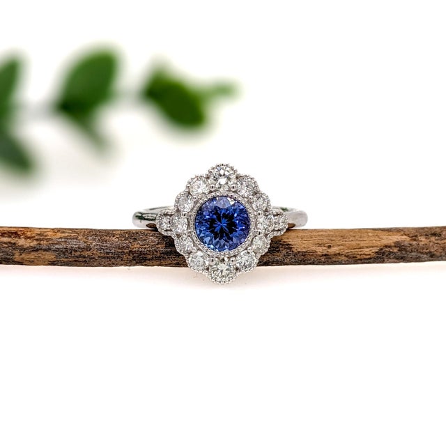 This beautiful ring features a 0.99 carat Tanzanite gemstone, encircled by a halo of natural earth mined diamonds and...