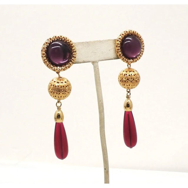 This is part of Chairish’s Costume Jewelry assortment. Goldtone filigree tops with cabochon faux-amethyst centers filigree...