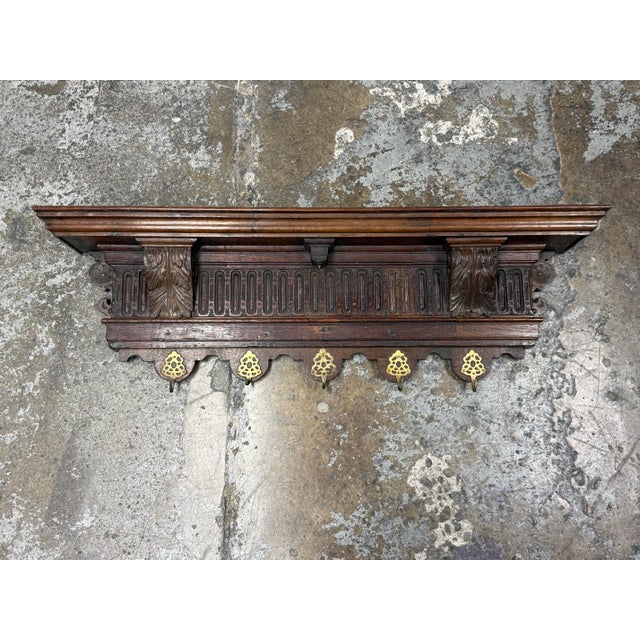 Design Plus Gallery presents an Antique Italian Walnut Carved Hanging Coat Rack. A molded upper shelf crowns a decorative...