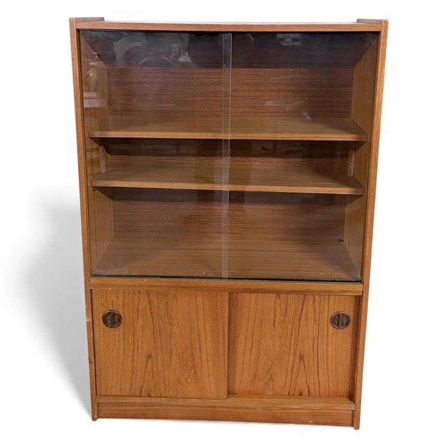 The Danish sliding glass bookcase is a mid century teak veneer cabinet designed to combine style and function, offering a...