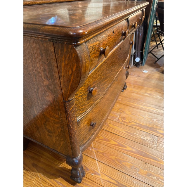 This antique piece is an early 20th-century American Tiger Oak dresser featuring a matching tilt oval beveled mirror....