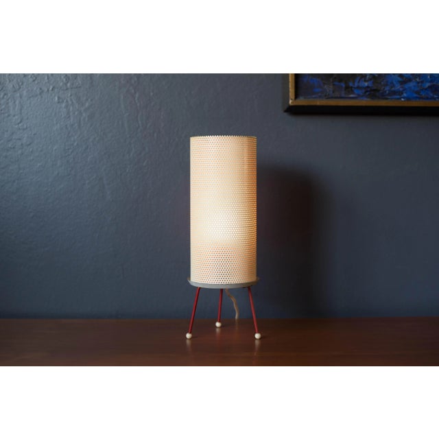 Vintage atomic tripod table lamp, circa 1950s. This unique piece features a cylinder perforated metal shade supported by a...