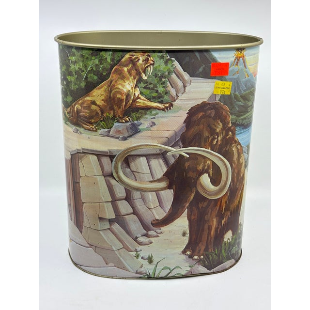 1987 vintage metal wastebasket that is double sided with dinosaurs on one side and mammoths/ sabertooth Tiger on the other...
