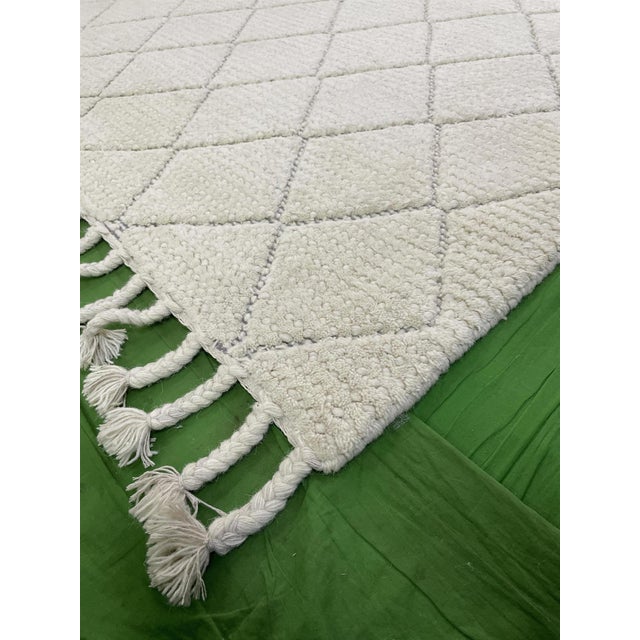 This contemporary Moroccan-style wool rug features an allover geometric pattern complemented by fringes. The field color...