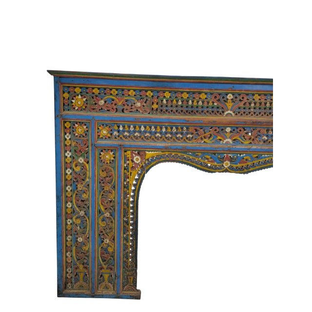 A large and richly decorated wooden fireplace surround, carved and painted in the vibrant polychrome tradition of early...