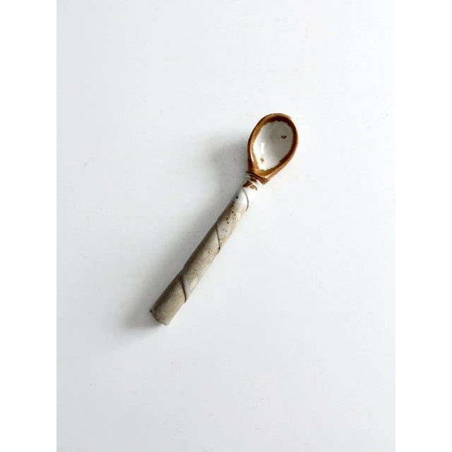 Here is a vintage studio pottery spoon. The hand-crafted serving utensil has a soft gray and white glaze with warm russet...