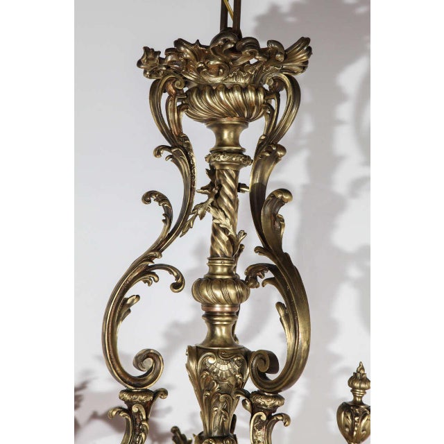 Ornate cast brass French chandelier designed circa 1890. This late 19th century piece includes floral glass shades to...