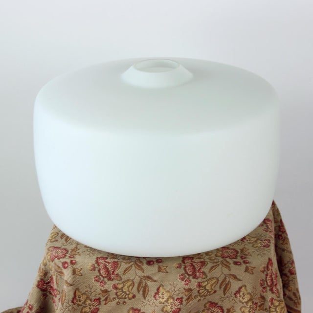 A striking ceiling light shade in pure white opaline glass, defined by its minimalist form and elegant proportions. The...