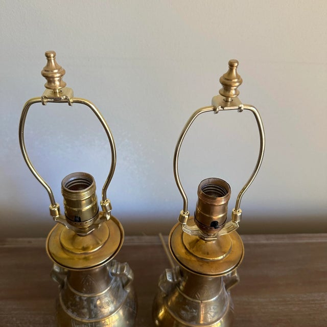 Pair of small brass engraved boudoir lamps with urn style bodies. The engravings on the lamps look to be done by hand and...