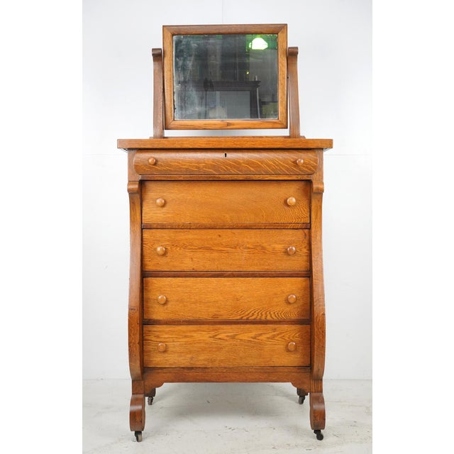 Antique American Empire bedroom dresser made of quarter sawn oak. It features sleigh style curved front pillars, five...