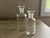 This pair of vintage Pyrex apothecary bottles offers a sleek, industrial-chic aesthetic perfect for a modern vanity, bar...