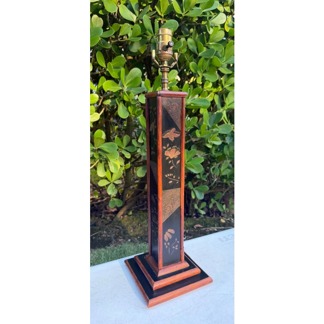 A distinctive vintage table lamp by Palecek featuring a tall, architectural silhouette with genuine rattan detailing, warm...