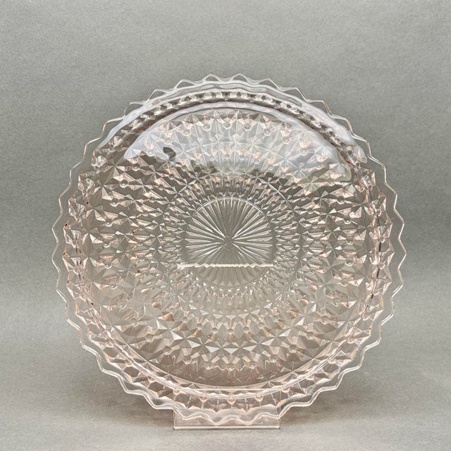 This gorgeous pink depression-era glass cake plate features the highly collectible Holiday pattern, also known as Buttons...