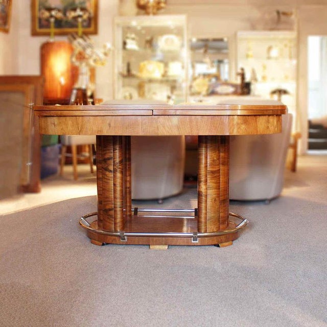 An Art Deco extending table in figured walnut with slide out, straight grain walnut leaves. Chromed metal footrest to...
