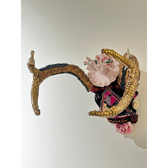 Delightful mixed media skull wall sculpture titled “Giving Sweet”, having a mix of crazy quilt, gold lame bits and pieces,...