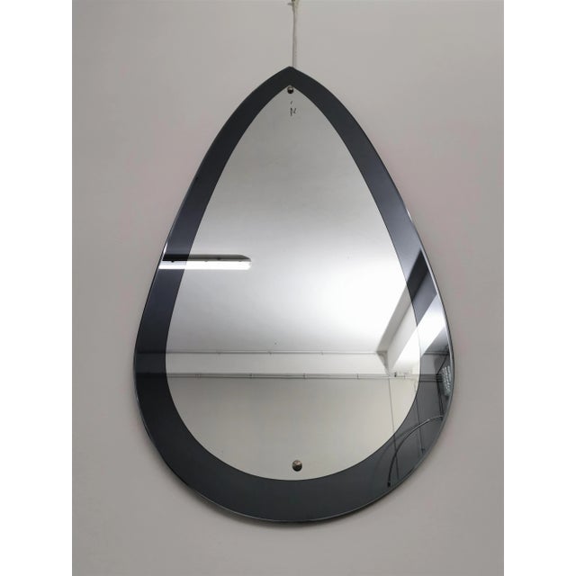 Drop wall mirror with considerable size produced in Italy in the 70s. The mirror was made with a dark gray mirrored glass...