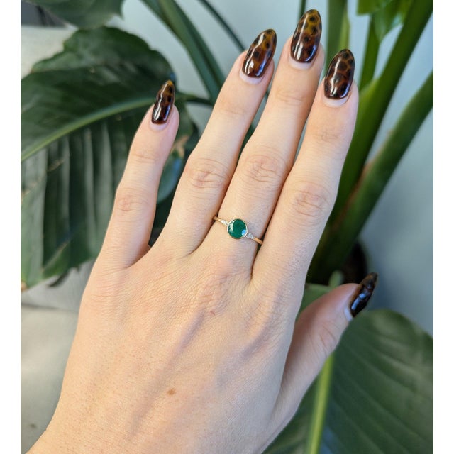 A 0.89ct zambian emerald round ring set in solid 14K yellow gold, set with six earth mined diamonds. Emerald, the May...