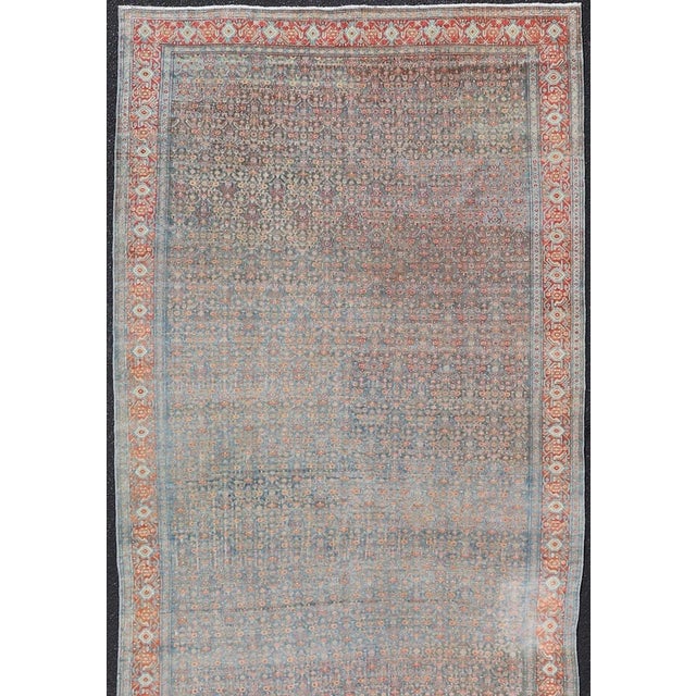 This antique Persian long gallery Senneh rug has been hand-knotted in wool. The rug features an all-over sub-geometric...
