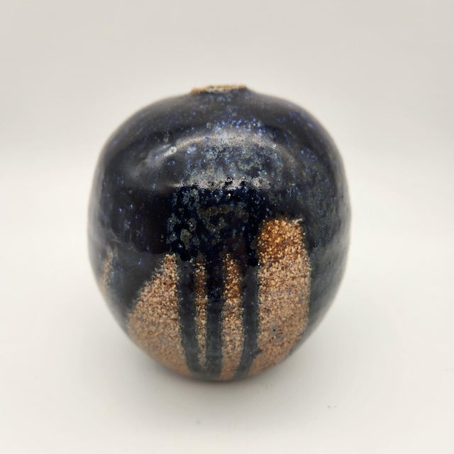 Spherical stoneware weed pot with deep cobalt-blue speckled glaze over exposed sandy clay body, small pinched opening, and...